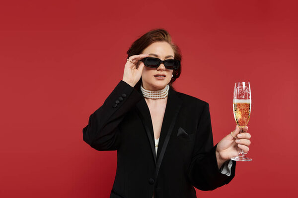 A stylish woman in chic attire enjoys a drink, showcasing her fashion sense and poise.