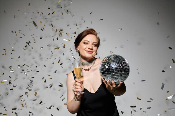 Элегантная женщина с радостью проводит дискотечный бал и шампанское в окружении праздничных конфетти.