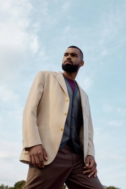 Şık bir sonbahar elbisesi içinde, yakışıklı bir adam resmedilmeye değer doğal bir ortamda rahatça poz verir..
