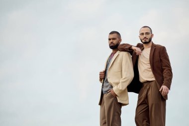 Handsome men in fashionable outfits pose confidently amidst an autumn landscape, capturing seasonal elegance. clipart