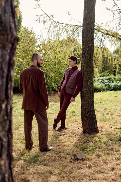 Два модных мужчины делят мгновение на живописном осеннем поле, ценя сезонный шарм.