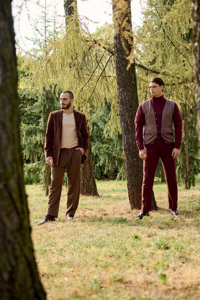 Двое хорошо одетых мужчин уверенно позируют в спокойном поле, обнятом цветами осени..