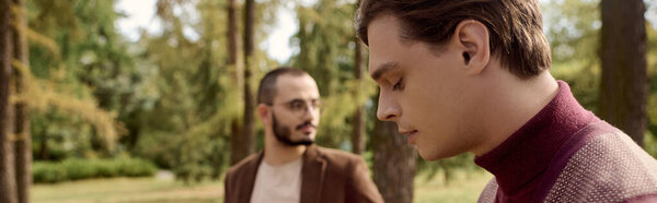 Handsome men in fashionable autumn outfits enjoy a tranquil moment in a picturesque natural setting.