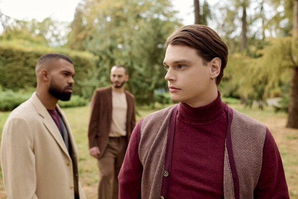 Три стильно одетых мужчины позируют в спокойном поле, наполненном яркими осенними красками..