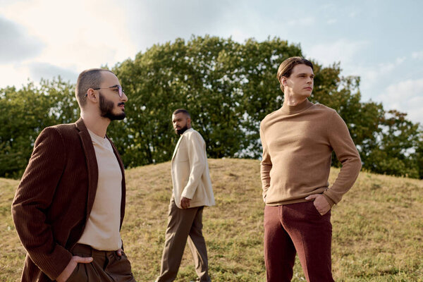Красивые мужчины, одетые в модный осенний наряд уверенно позируют в ярком поле в окружении природы.