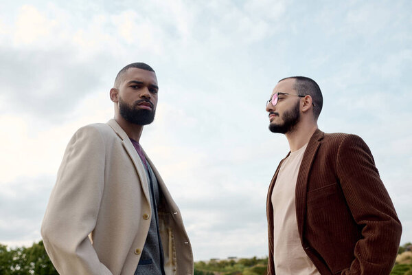 Два красивых мужчины элегантно одеты для осени, наслаждаясь красотой природы в спокойном осеннем поле.