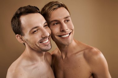 İki genç adam sıcak bir ortamda aşklarını ve mutluluklarını kucaklayarak gülümsüyor..