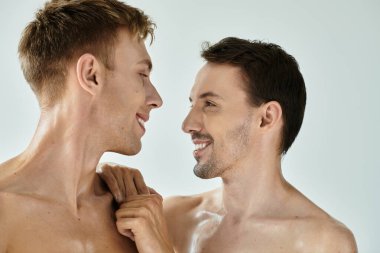 İki genç adam birbirlerinin gözlerinin içine bakar. Minimalist bir alanda sevgi ve bağlantı yayarlar..