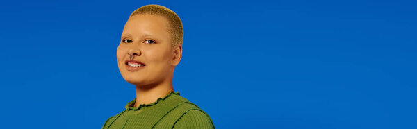 Модная молодая женщина ярко улыбается, излучая радость и уверенность в себе в поразительной обстановке.