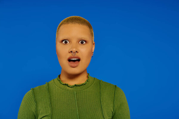 A young woman with a trendy hairstyle exhibits a surprised expression in a colorful environment.