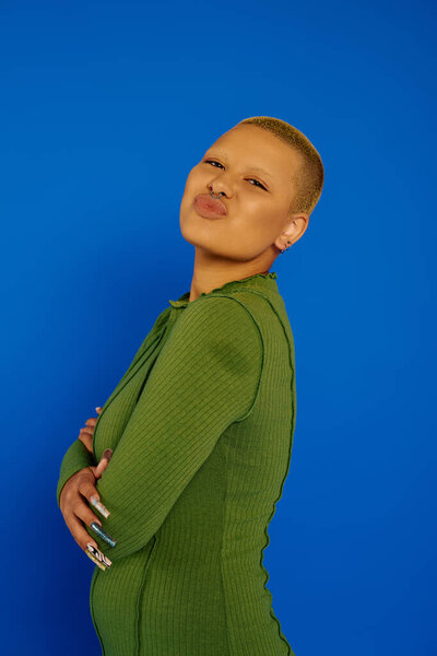 Модная женщина демонстрирует свой уникальный стиль с игривым выражением лица в красочной обстановке.