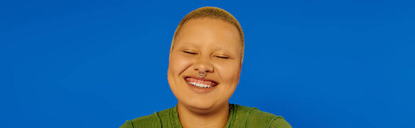 A young, fashionable woman beams with happiness, showcasing her unique style in a vibrant setting.