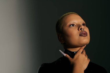 Şık bir genç kadın kendine has tarzını ve kendine güvenen ifadesini sergiliyor..