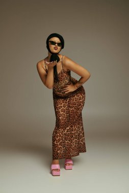 Modaya uygun genç bir kadın moda leopar desenli elbisesini sergileyerek eğlenceli bir poz veriyor..