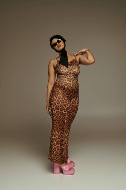 A fashionable young woman showcases her unique style in an animal print dress while striking a pose. clipart