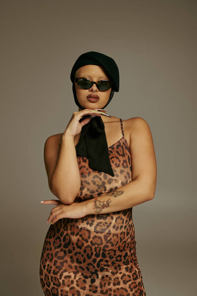 Молодая женщина уверенно позирует в шикарном леопардовом платье, источая современные модные флюиды.