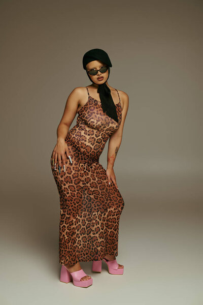 A young woman showcases her fashion sense with leopard print attire and playful pink heels.