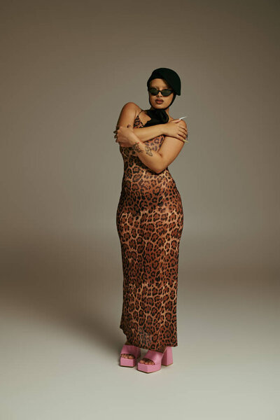 Стильная молодая женщина уверенно позирует со скрещенными руками, обнимая свой модный взгляд вперед.