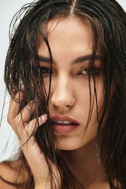 Çekici bir kadın, ıslak saçlarıyla, yüzünü güzellikle ve zahmetsizce çerçevelemektedir..