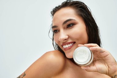 Neşeli bir kadın cilt bakımını ön plana çıkarır, kendine güveni ve güzelliği parlak bir ortamda yayar..