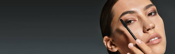 Красивая женщина пристально фокусируется, нанося макияж глаз с художественным чутьем при тусклом освещении.