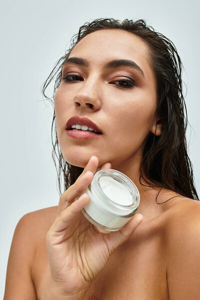 Женщина демонстрирует продукт по уходу за кожей, излучая сияющую и уверенную ауру..