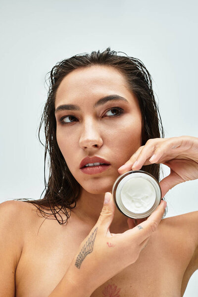 Женщина выделяет роскошный крем для кожи, представляя помолвленное выражение лица.