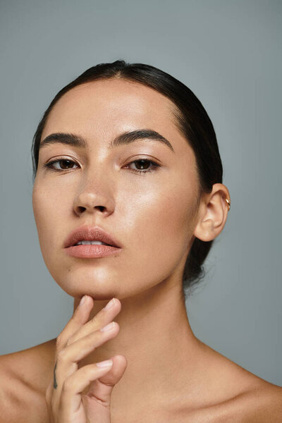 Уравновешенная женщина нежно касается ее лица, излучая элегантность и уверенность в спокойной обстановке.