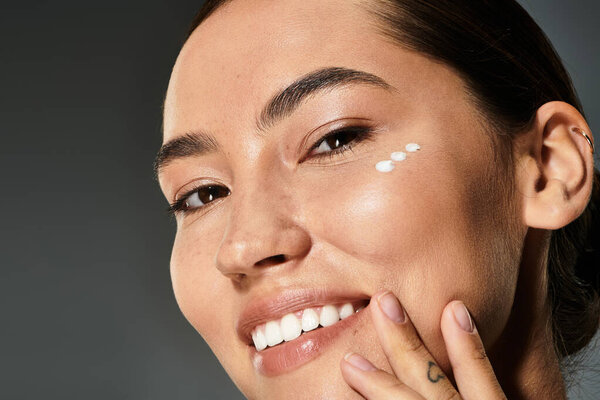 A joyful woman is enhancing her natural beauty while applying skincare in a stylish environment.