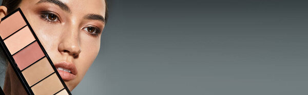 Женщина держит яркую палитру макияжа, подчеркивая свою сияющую красоту и стиль