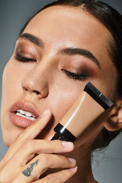 Красивая женщина улучшает свои черты при нанесении макияжа, демонстрируя артистичность и сдержанность.