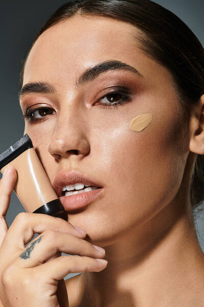 A beautiful woman showcases her makeup technique, holding foundation with confidence and grace.