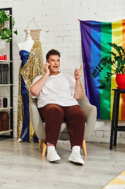 Çekici bir eşcinsel şık bir sandalyeye rahatça oturur ve telefonda canlı canlı konuşur..