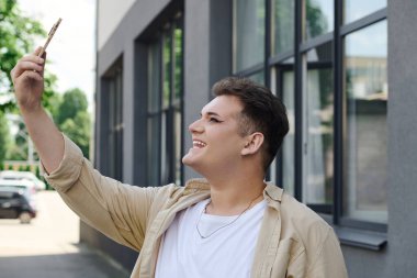 Neşeli bir insan neşeyle dışarıda bir selfie çeker, güneş ışığı gülümsemesini aydınlatır..