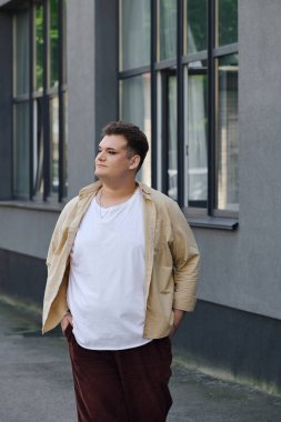 Moda düşkünü, tuhaf bir insan, özgünlüğünü ifade eden modern bir binanın yanında düşünceli bir şekilde durur..