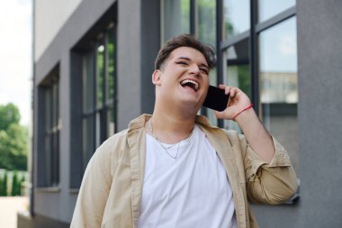 Eşcinsel bir birey şık bir yapının dışında dururken canlı bir telefon konuşmasından zevk alır..