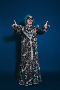 Çarpıcı mavi saçlara sahip etkileyici bir insan benzersiz kıyafetlerini coşku ve neşeyle sergiliyor..