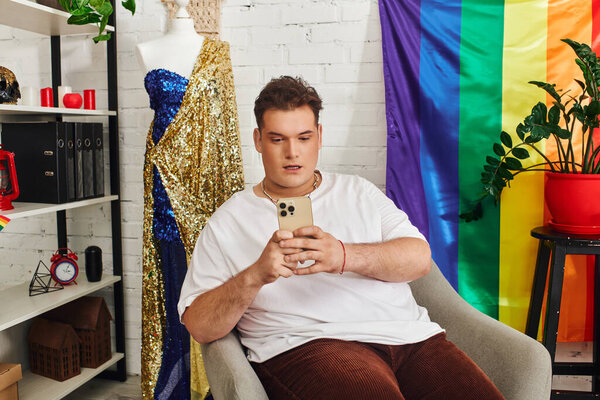 A unique person interacts with their phone in a vibrant, pride colored space.