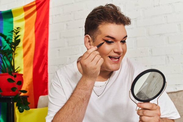 An expressive queer person enjoys a moment of makeup application, radiating joy and confidence.