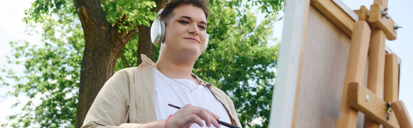 A unique person creates vibrant art on a canvas in a sunny outdoor setting.