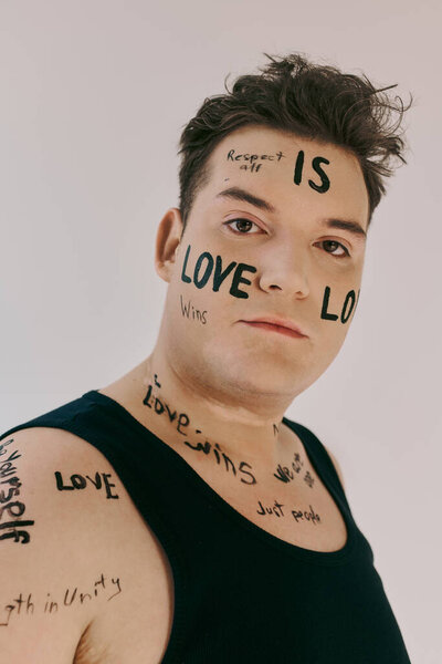 Привлекательный человек, демонстрирующий послания любви и уважения на своей коже в творческом пространстве.