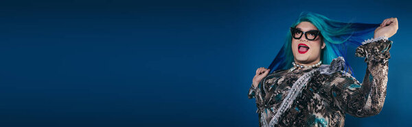 A confident person with striking hair celebrates individuality in a creative and colorful outfit.