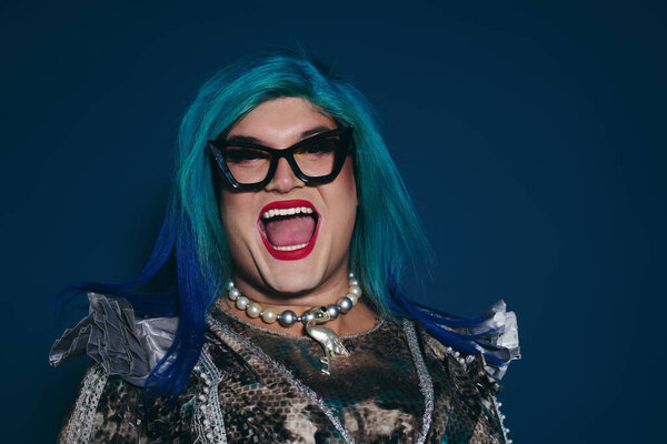 Экспрессивный человек с яркими голубыми волосами излучает счастье в творческой обстановке.