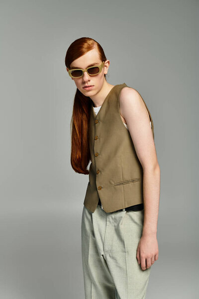 A teenage boy showcases a trendy smart casual look with red hair, styled elegantly against a simple grey background.