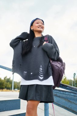 Genç bir Asyalı öğrenci, dışarıda arkadaşlarıyla eğlenirken şık bir kıyafete güvenir..