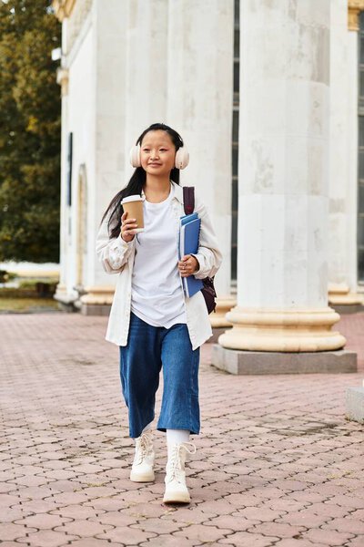 Молодая азиатка пьет кофе и гуляет по университетскому городку, обнимая молодежь и разнообразие..