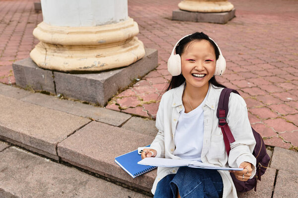 Веселая студентка университета проводит свои занятия на улице, демонстрируя молодость и разнообразие в кампусе.