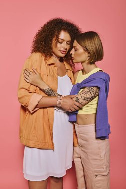 A joyful lgbt couple shares a tender moment, celebrating love against a pink backdrop in a studio. clipart