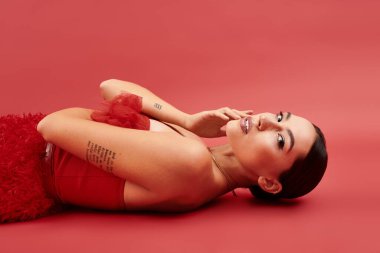 Bu genç kadın çarpıcı bir kırmızı arka plana karşı poz verirken güzellik ve güven yayıyor..