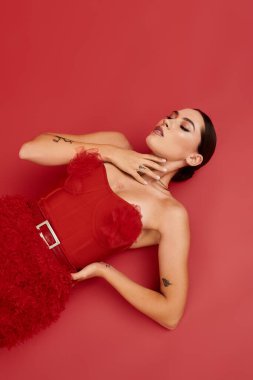 Çarpıcı genç bir kadın, poz verirken çarpıcı kırmızı bir elbiseyle zarafet sergiliyor..